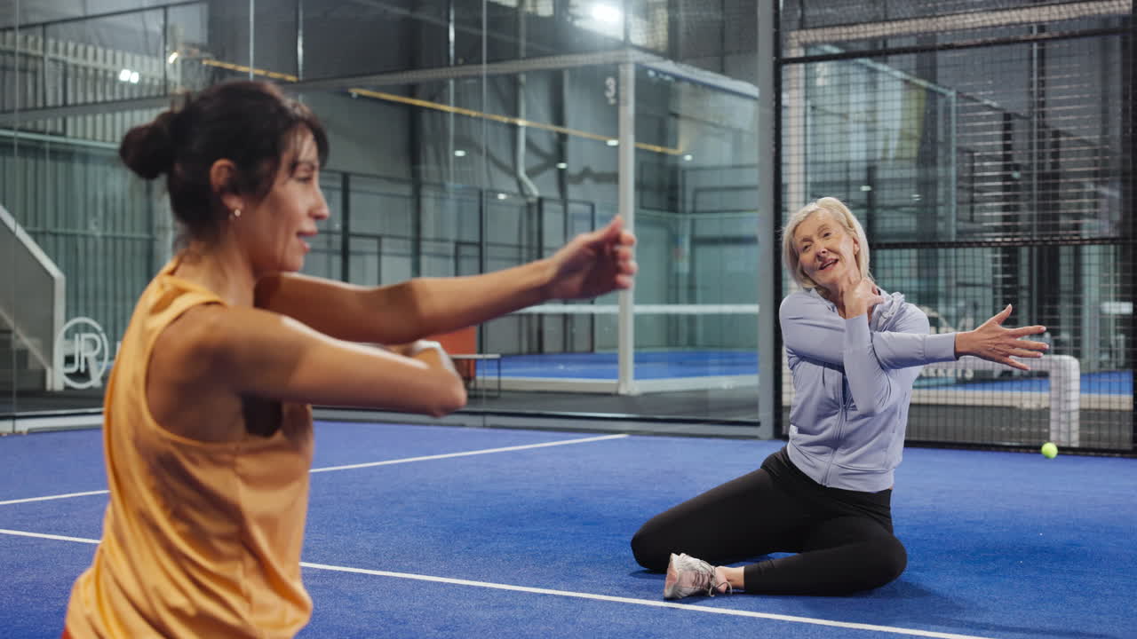 To kvinner som tøyer på en padelbane