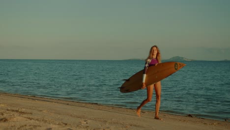 woman walking on the beach with surfboard