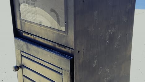 una vieja caja de periódicos pintada de negro con un periódico falso dentro