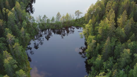 aerial drone shot of a narrow ridge in the middle of a small calm lake by sunset