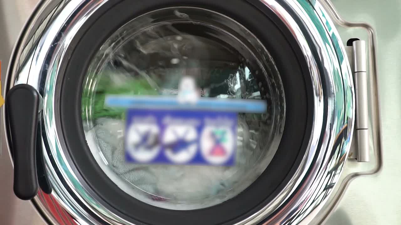Washing machine door with rotating garments inside. Dirty laundry concept