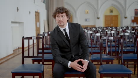 hombre de traje esperando en una iglesia vacía