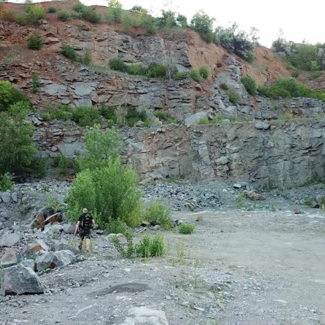 back view of a sporty tourist travelling through the rocky place near the beautiful lake. extreme hiker walking outdoors over the stony background.