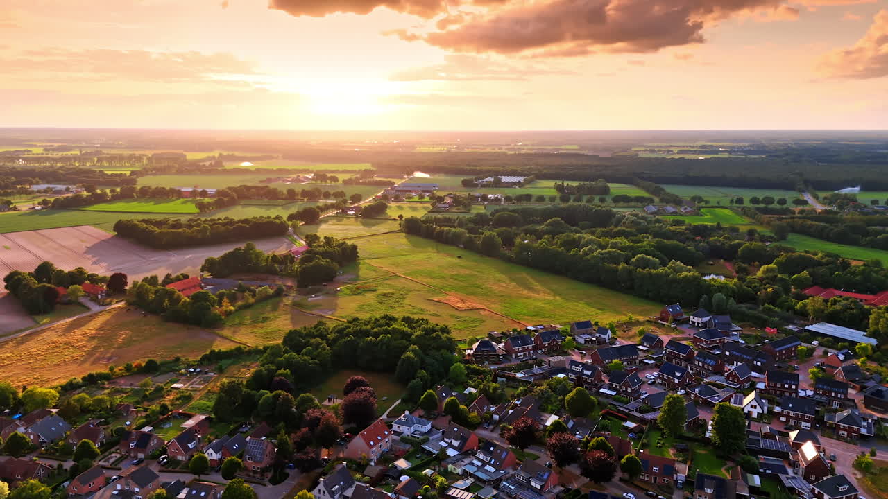 Footage over the picturesque rural area with densely built residential area. Beautiful countryside at sunset from drone