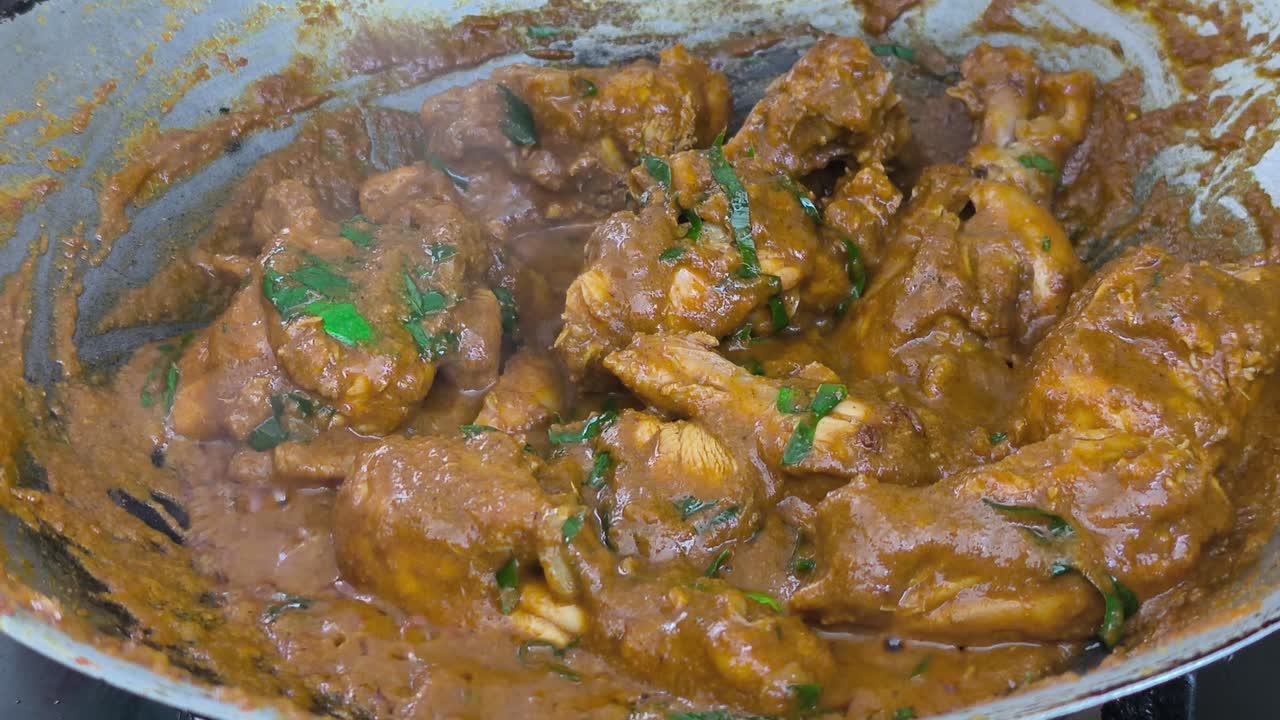 Uno chef cucina con cura del pollo fresco in un wok. Vengono aggiunte ricche spezie per il rendang, sprigionando un aroma appetitoso. Questo processo tradizionale assicura un sapore autentico e intenso.