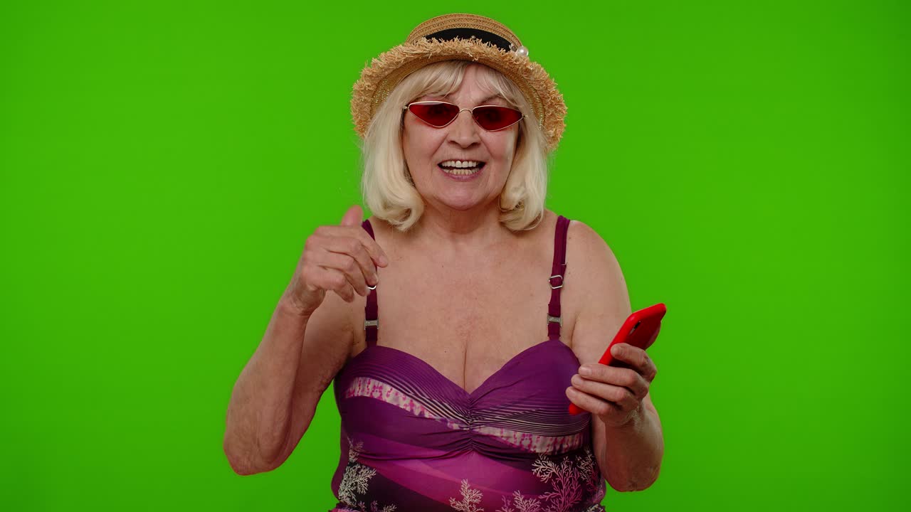 휴가 리조트 휴가를 축하하는 휴대전화와 함께 선글라스를 입은 고령 여성 관광객
