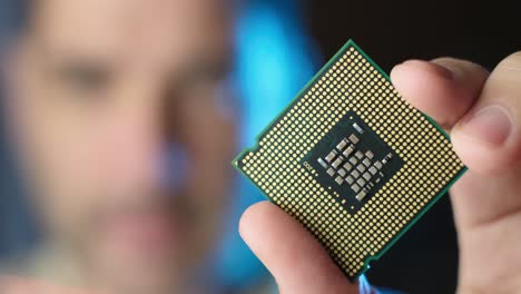 microchip cpu sostenido por macho, escaneando luz roja a través de su cara, enfocándose en primer plano