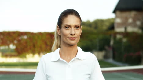 Retrato-De-Una-Hermosa-Mujer-Parada-En-Una-Cancha-De-Tenis-Sosteniendo-Una-Raqueta-Y-Sonriendo-Alegremente-A-La-Cámara-1