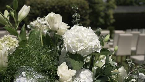 elegant outdoor floral arrangement featuring white hydrangeas, roses, and lilies, set for a wedding ceremony