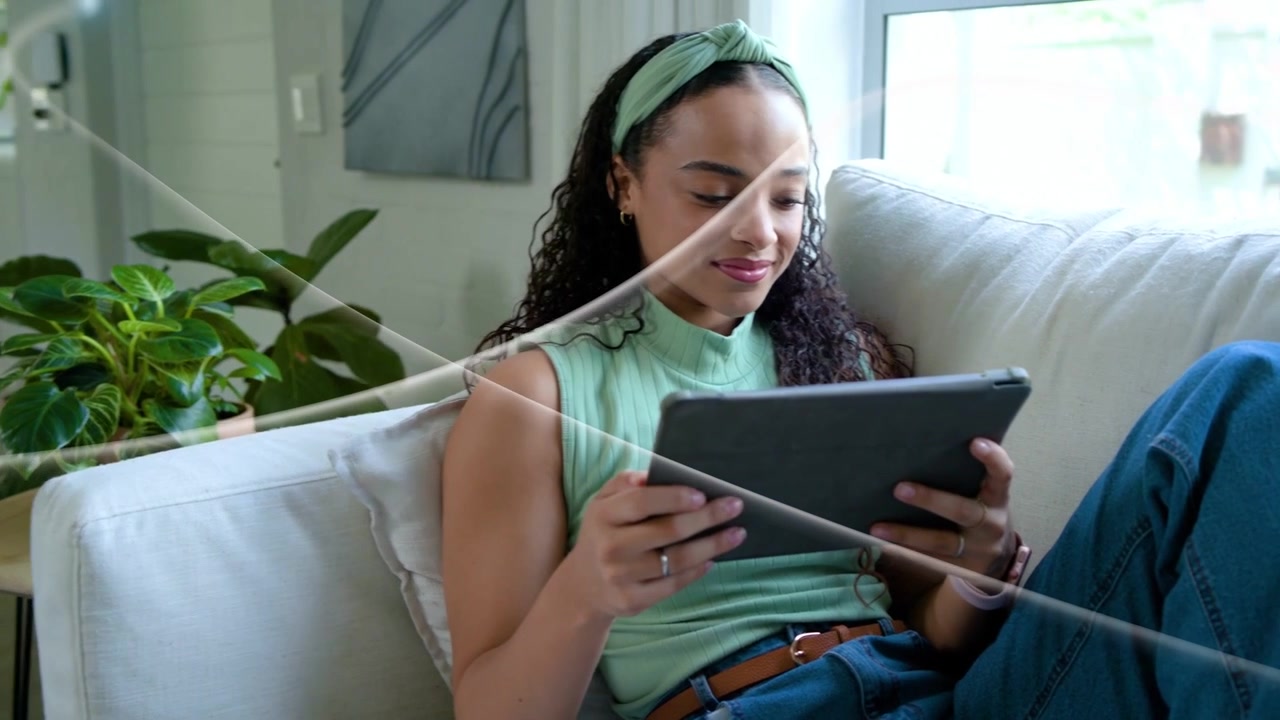Woman tapping tablet screen, causing light-streak sweeping over couch, showing technology