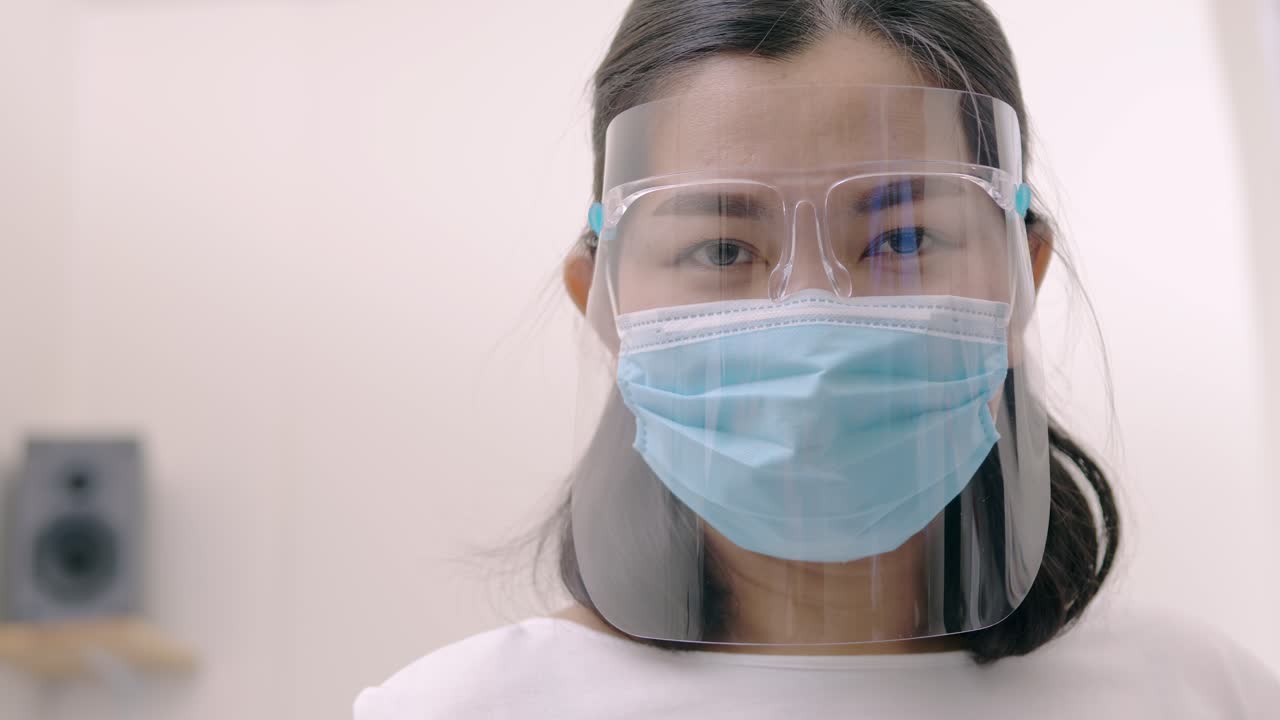 Portrait of an Asia young female who is wearing a face shield with mask rounded around her face from a frontal perspective to protect her glasses and eyes, scene of slow motion