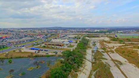 drone footage of the flood plain with shops, car parks and road or highway of to the sides moving backwards