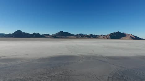 una toma aérea de un dron revela agua suave que cubre la lama blanca de las salinas de bonneville y las montañas distantes