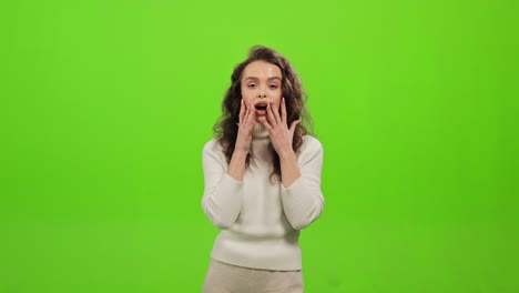 la donna è in piedi e guarda la telecamera. è sorpresa e molto felice. è in piedi su uno sfondo verde. schermata verde. 4k.