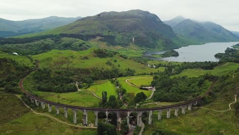 jacobite steam train approaching glenfinnan viaduct as swifts fly near camera, aerial