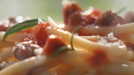 macro toma de espagueti bolognese salpicado con queso parmesano rallado y adornado con hojas de romero frescas - la cámara se mueve hacia la izquierda