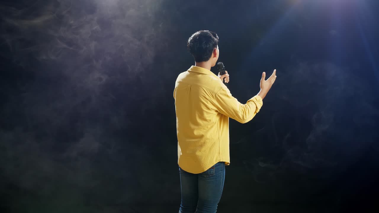 백색 연기 검은 배경에 마이크를 들고 노래하는 어린 소년의 뒷면