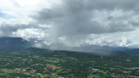 aerial footage, pai in northern thailand shows sweeping valley landscape with storm clouds releasing. a dramatic contrast of light and shadow captures nature’s intensity in a peaceful rural setting