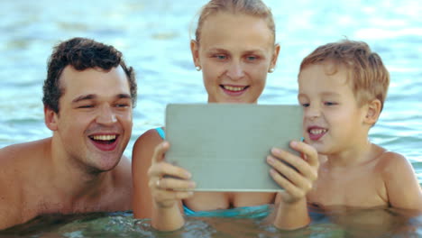familia de tres en el mar viendo algo en la plataforma