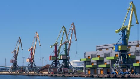 port cranes and harbor warehouses in sunny calm summer day at port of ventspils, wide shot from a distance