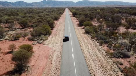 Toma-Aérea-De-Un-Todoterreno-Conduciendo-Por-Una-Carretera-Larga-Y-Recta-A-Través-Del-Interior-Implacable-De-Australia