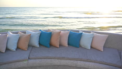 a colorful row of decorative pillows along the back of a seat looking out at the ocean