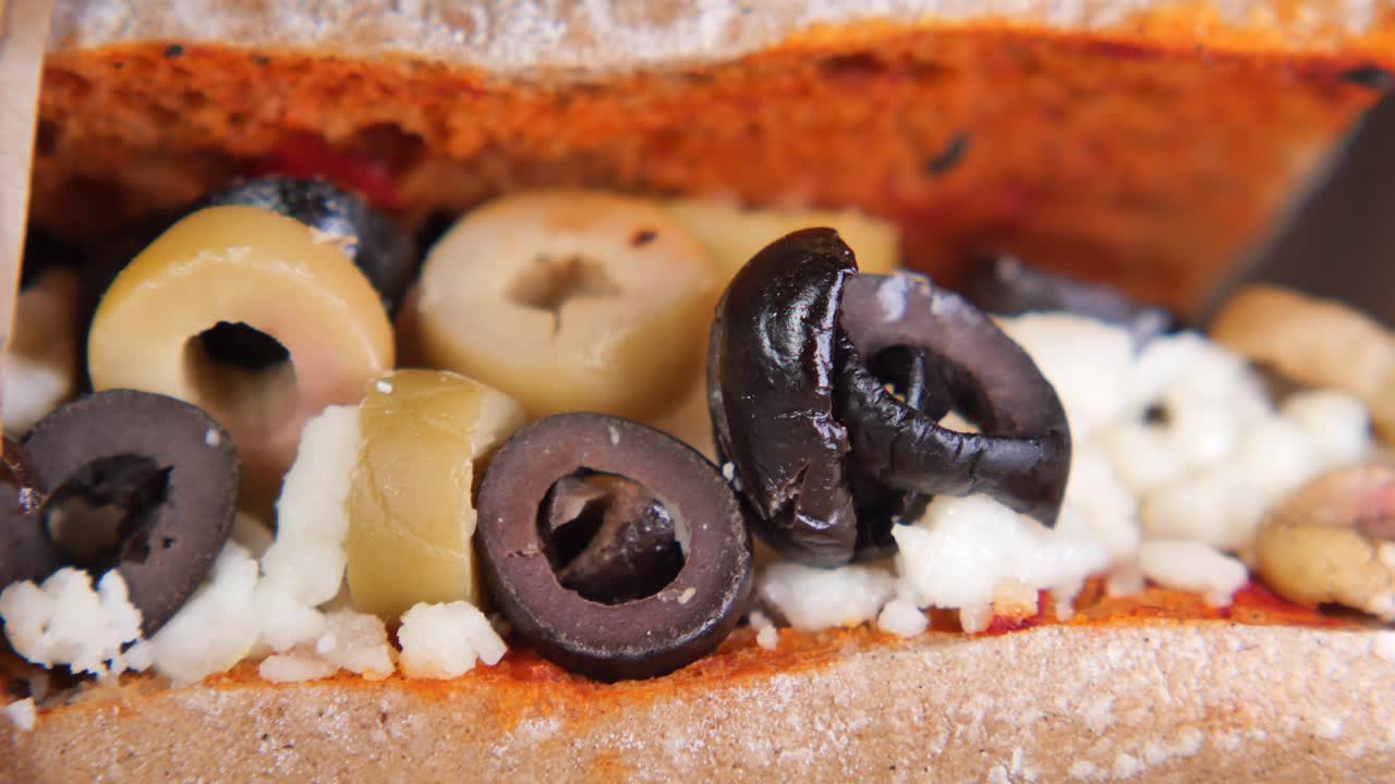 Primo piano di un panino con olive nere e verdi e formaggio