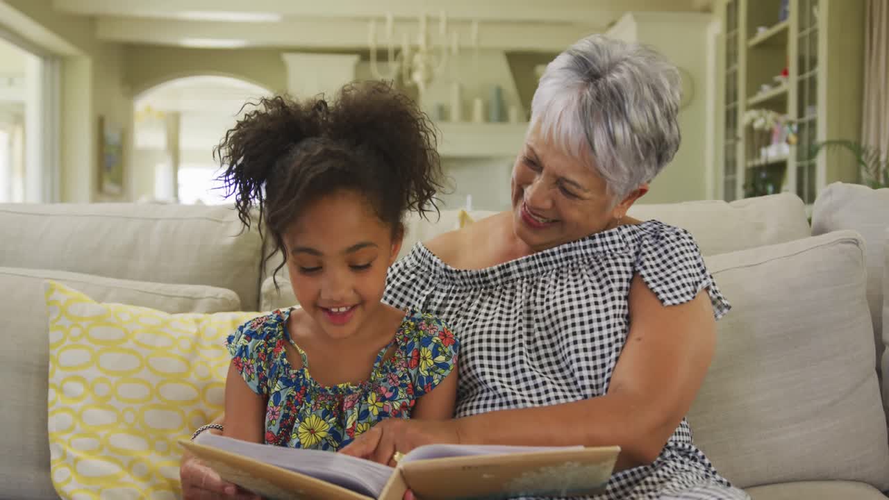 abuela y nieta leyendo un libro en casa
