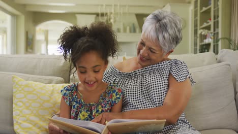 grandmother and granddaughter reading book at home