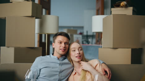 new homeowners sitting couch in room with boxes close up. family relocation.