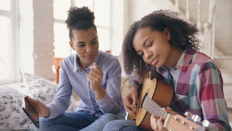two girls learning guitar