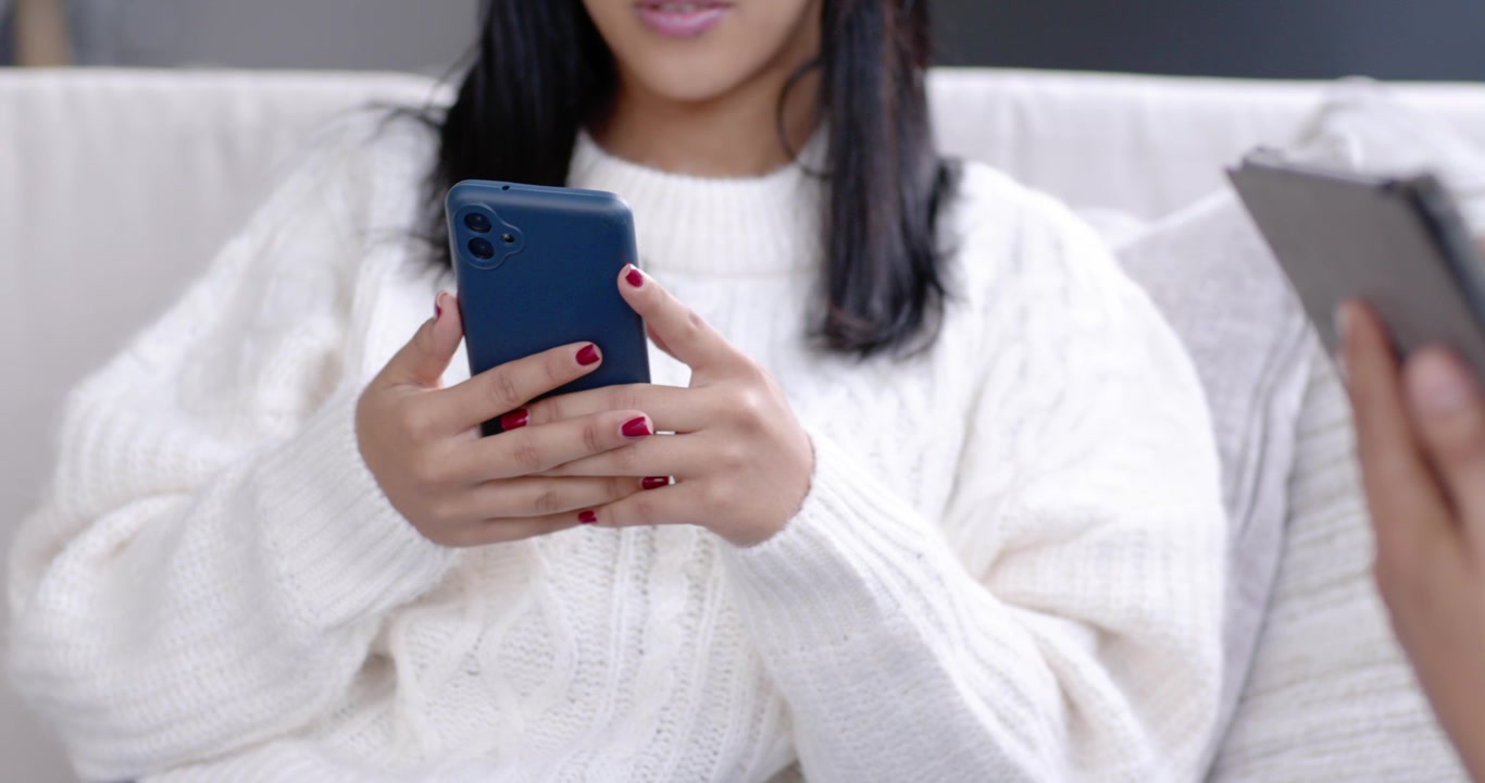La telecamera si allontana mentre una donna con uno smartphone blu tocca e scorre per controllare i messaggi