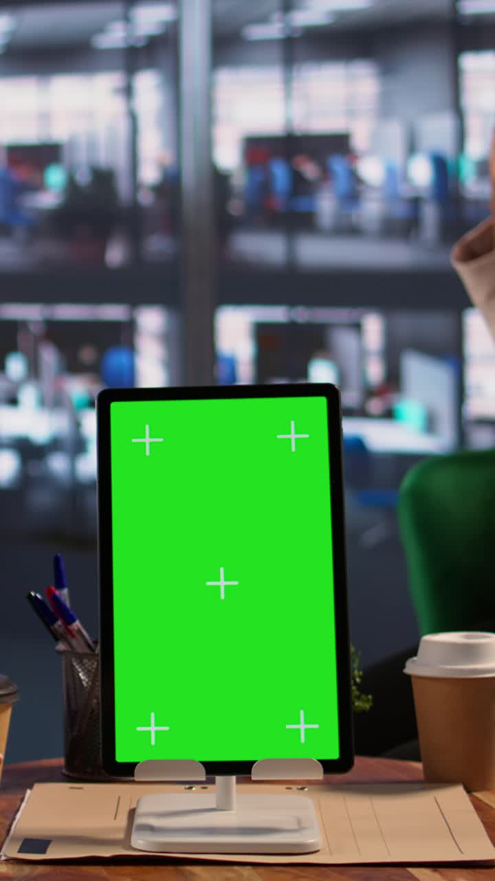 Tablet digitale con display a schermo verde sulla scrivania dell'ufficio