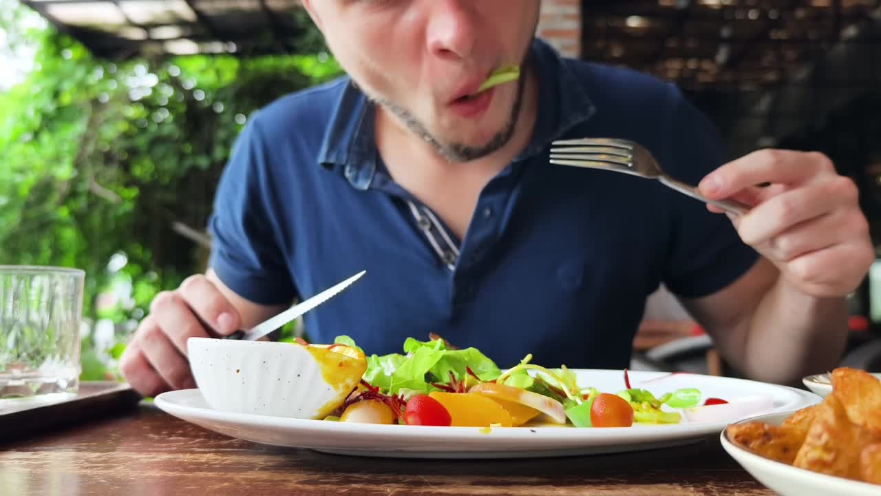 hombre comiendo ensalada en un restaurante