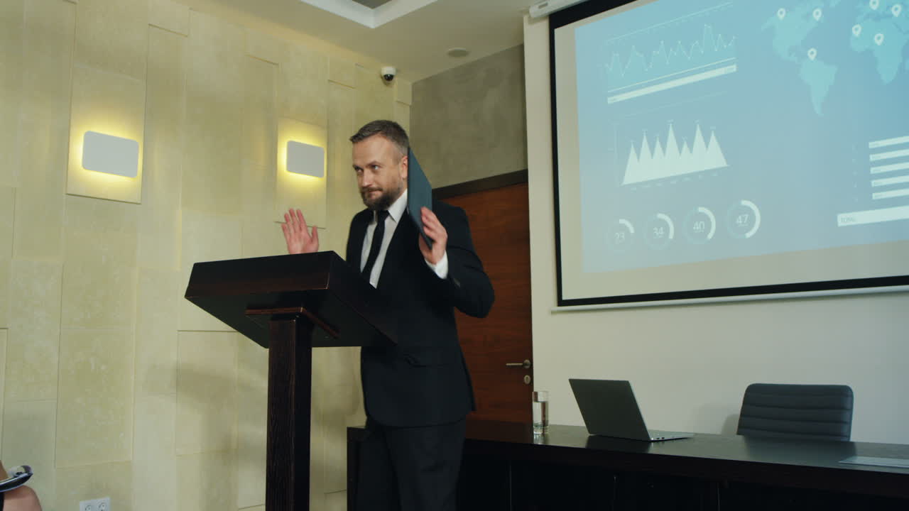 hombre de negocios caucásico entrando en una sala de conferencias mientras la gente aplaudía, luego sube al podio