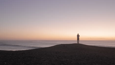 lonely person standing looking at dawn by the ocean with purple sky