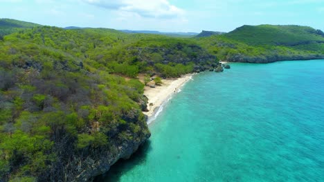 el dron se eleva a lo largo de un acantilado rocoso con la playa de arena dorada de san juan y el agua turquesa.
