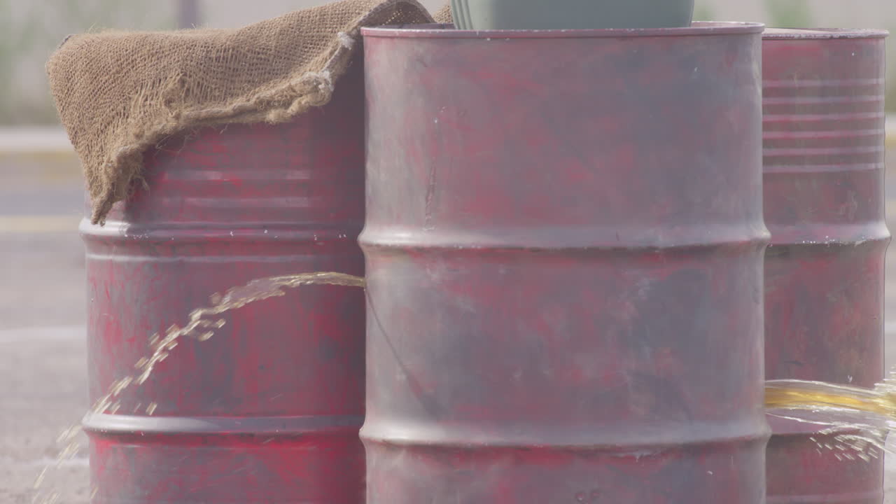 총알은 물로 가득 찬 빨간 금속 통에 구멍을 낸다