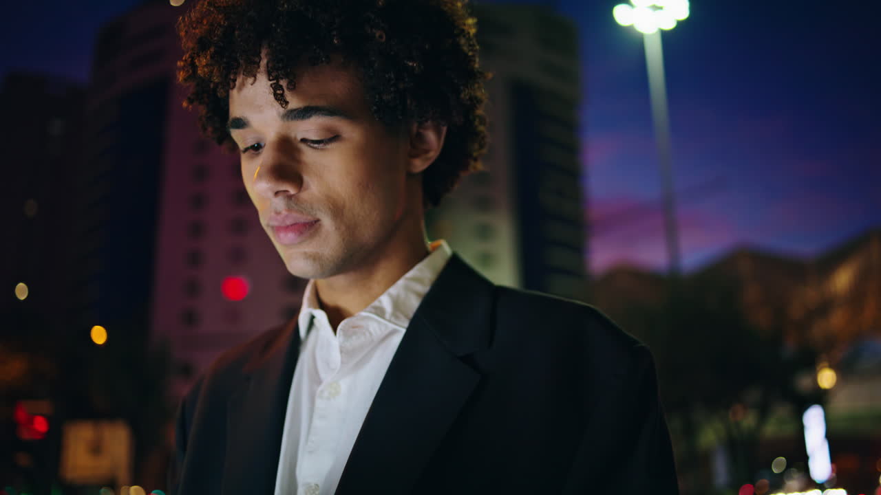 행복한 사업가 밤을 고 있는 도시 가까이에서 편안한 젊은이가 조용히 움직이고 있다.