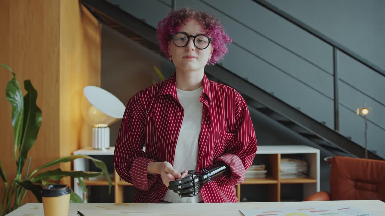 Businesswoman with Prosthetic Arm Talking at Camera via Video Call in Office