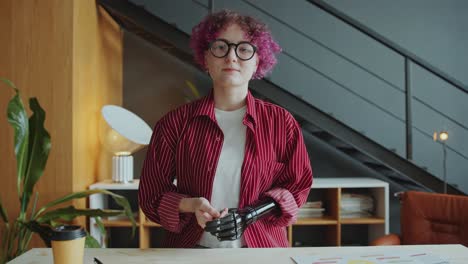businesswoman with prosthetic arm talking at camera via video call in office