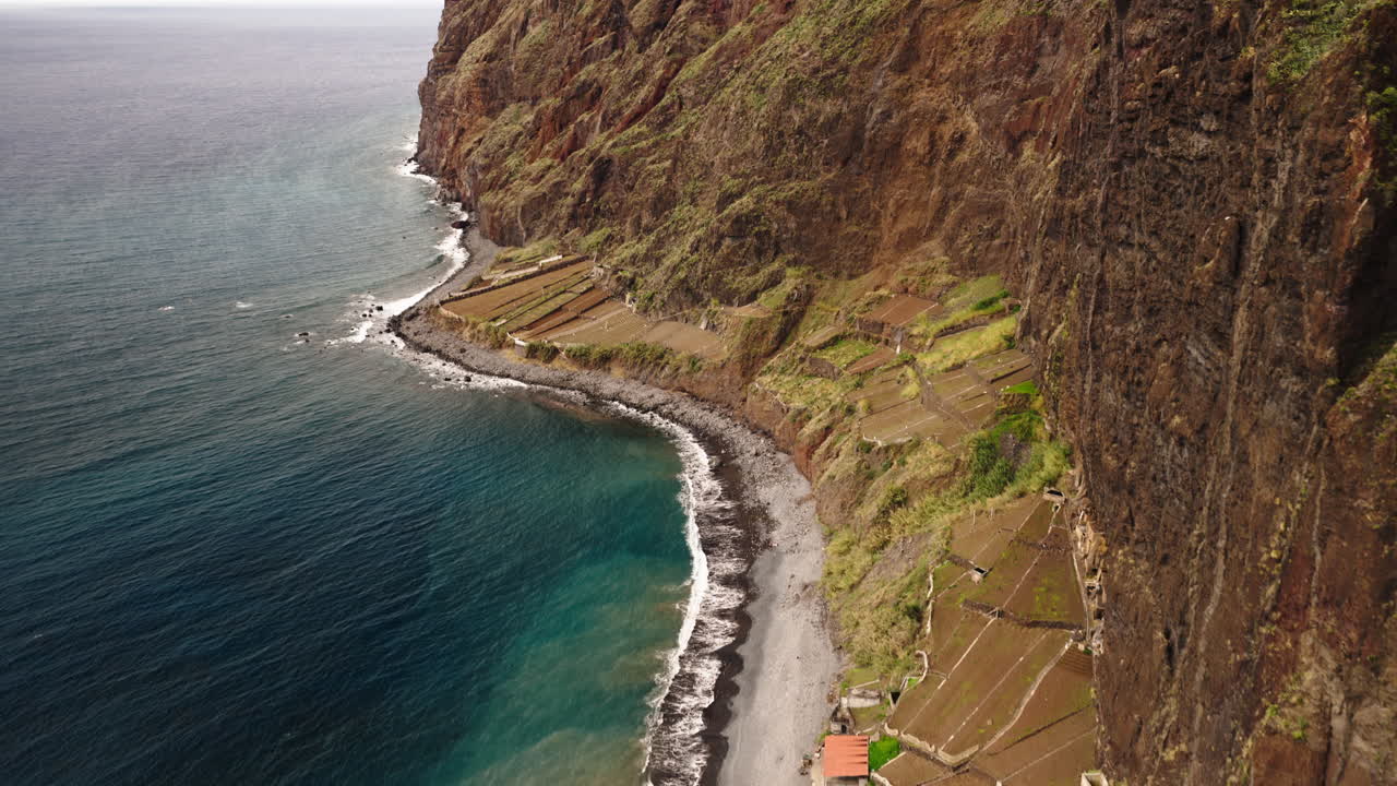 Vista aérea de un acantilado costero empinado con terrazas agrícolas y el océano