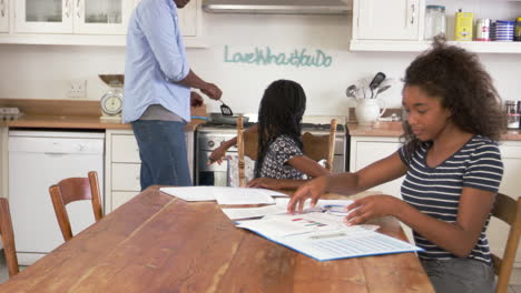 father helping two daughters sitting at table doing homework