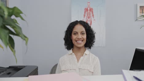 Portrait-of-medical-receptionist-sitting-at-front-desk,-smiling,-slow-motion