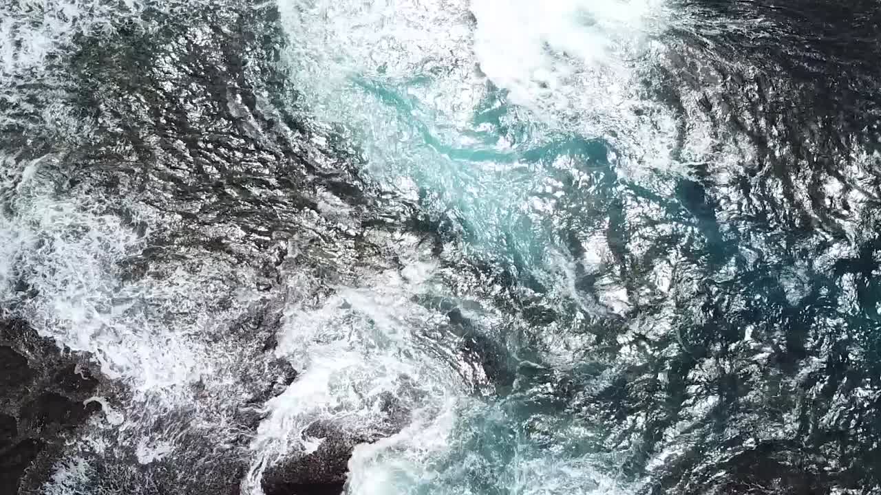 Vista a volo d'uccello di onde blu dell'oceano che si infrangono sulle rocce