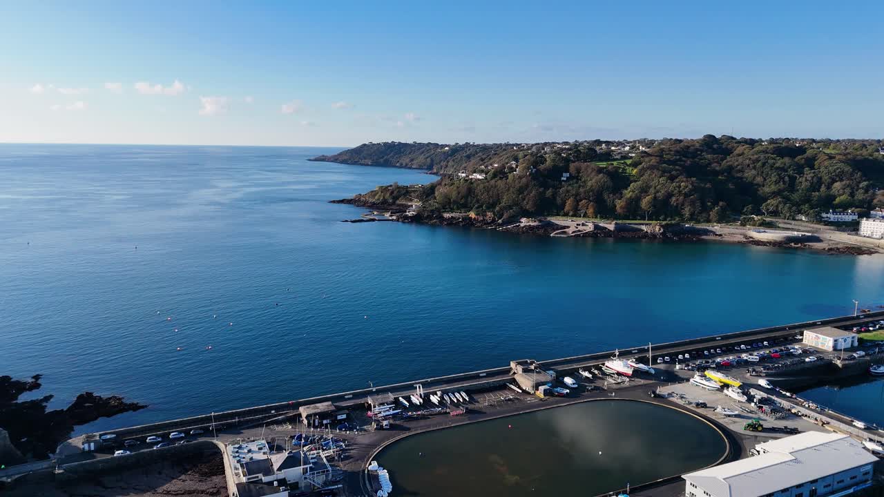 Riprese aeree con drone ad alta risoluzione della Baia di Havelet, St Peter Port, Guernsey, che mostrano l'intera baia, Albert Pier, il laghetto per modellini di yacht e il porto in una giornata calma sotto il sole del tardo pomeriggio, con vista su St Martin's Point