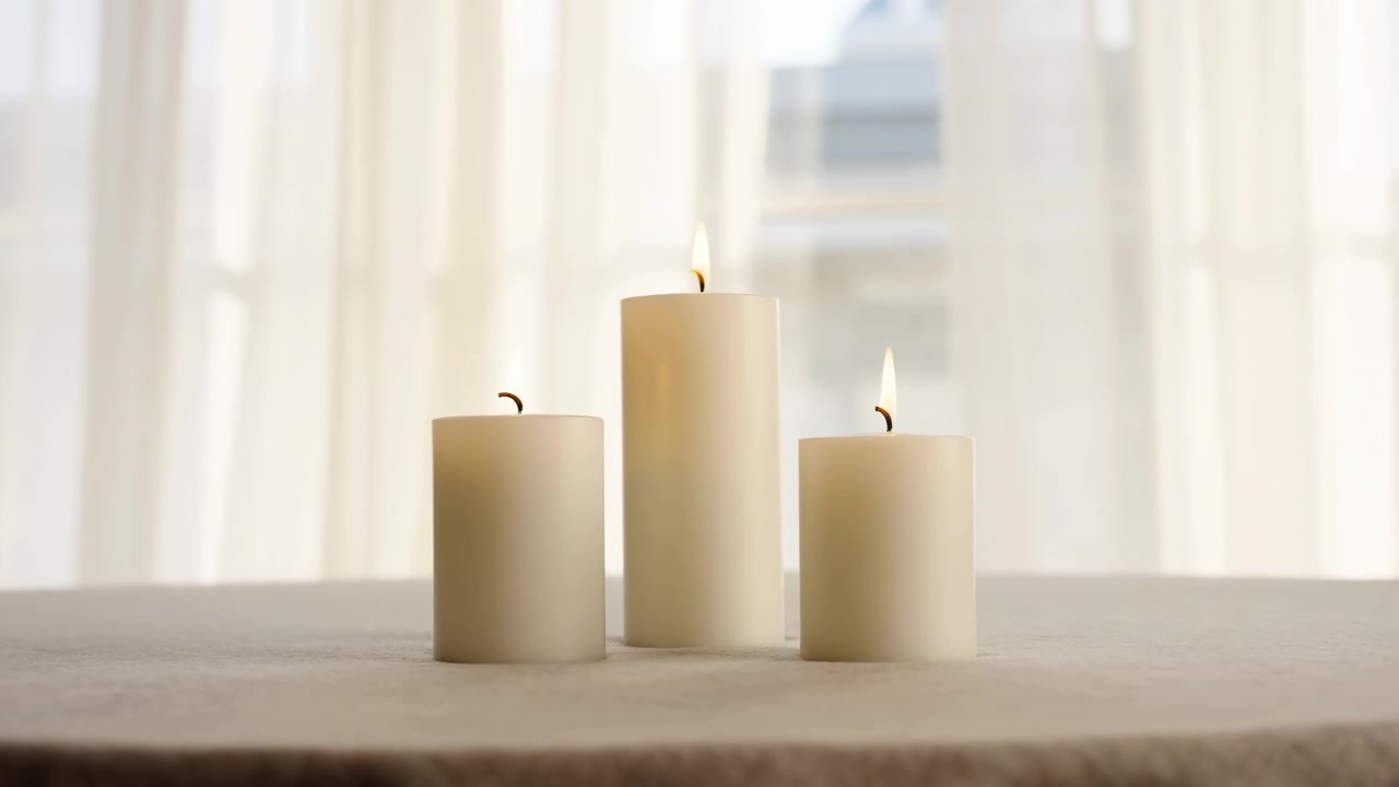 Una scena tranquilla con candele disposte in fila su un davanzale, adornato con tende velate e immerso nella luce naturale. Questa ambientazione serena e pacifica è un elemento d'arredo, evocativo