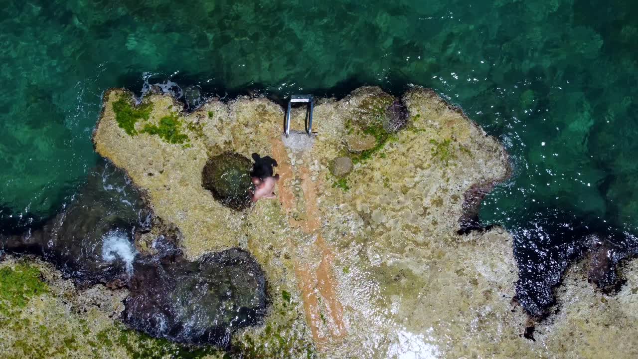 el hombre camina sobre afloramientos con un agujero en la playa de anfeh junto al mar azul claro en el líbano