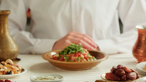person holding a plate of salad with dates and nuts on a table