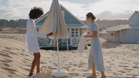 girls resting beach picnic at coastline houses. happy friends preparing spot